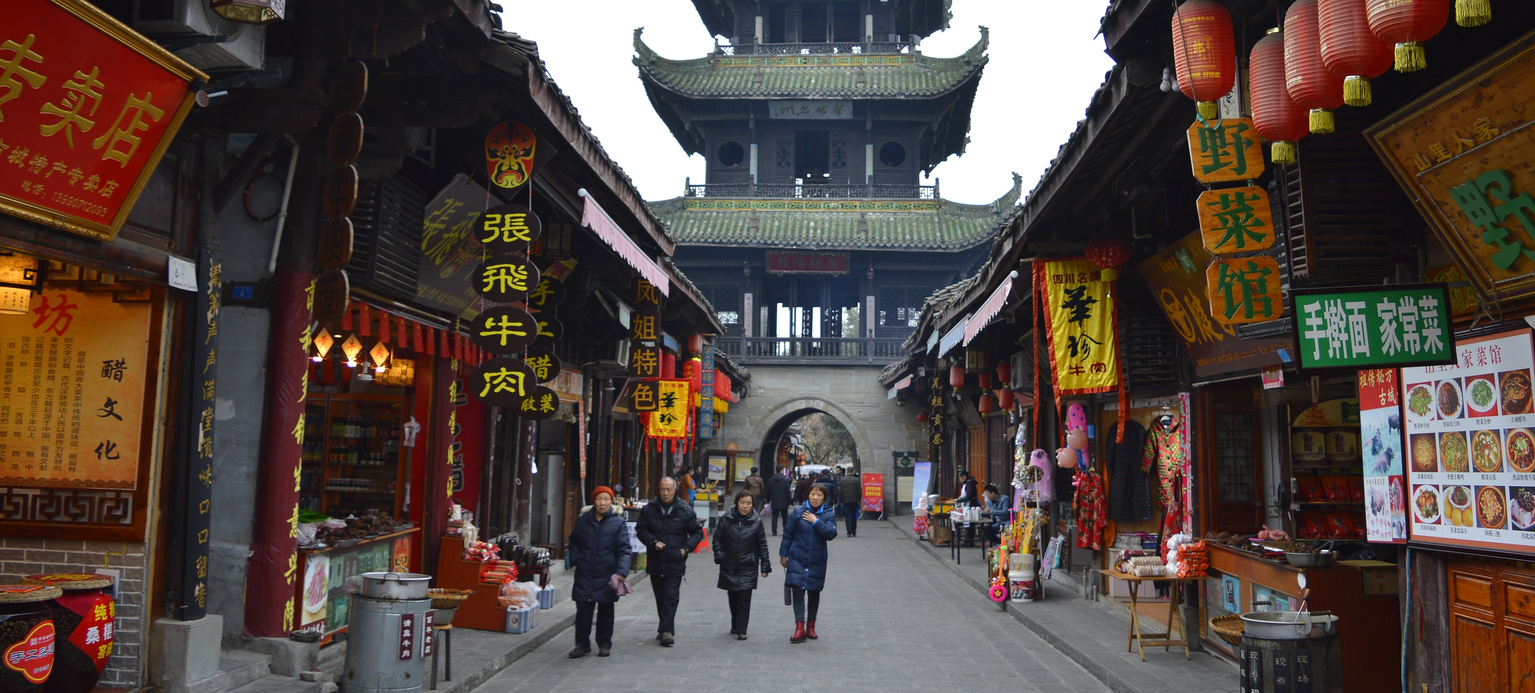 Menschen laufen durch eine Straße mit Ständen für chinesisches Essen. Am Ende der Straße ist ein e Pagode